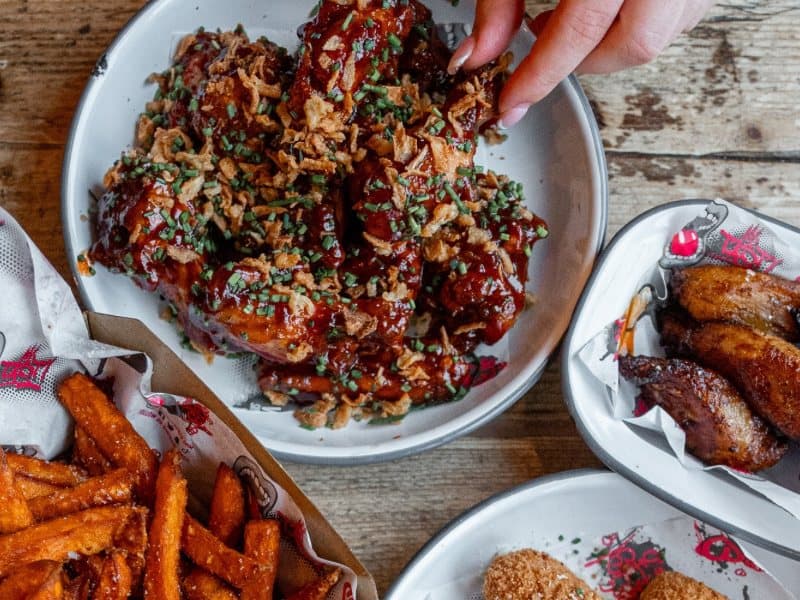 Wings in sauce on a shared table with sweet potato fries